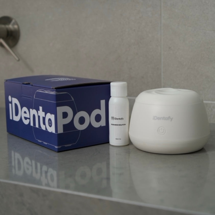 iDentaPod product set including a box, cleaning solution, and device on a reflective surface.